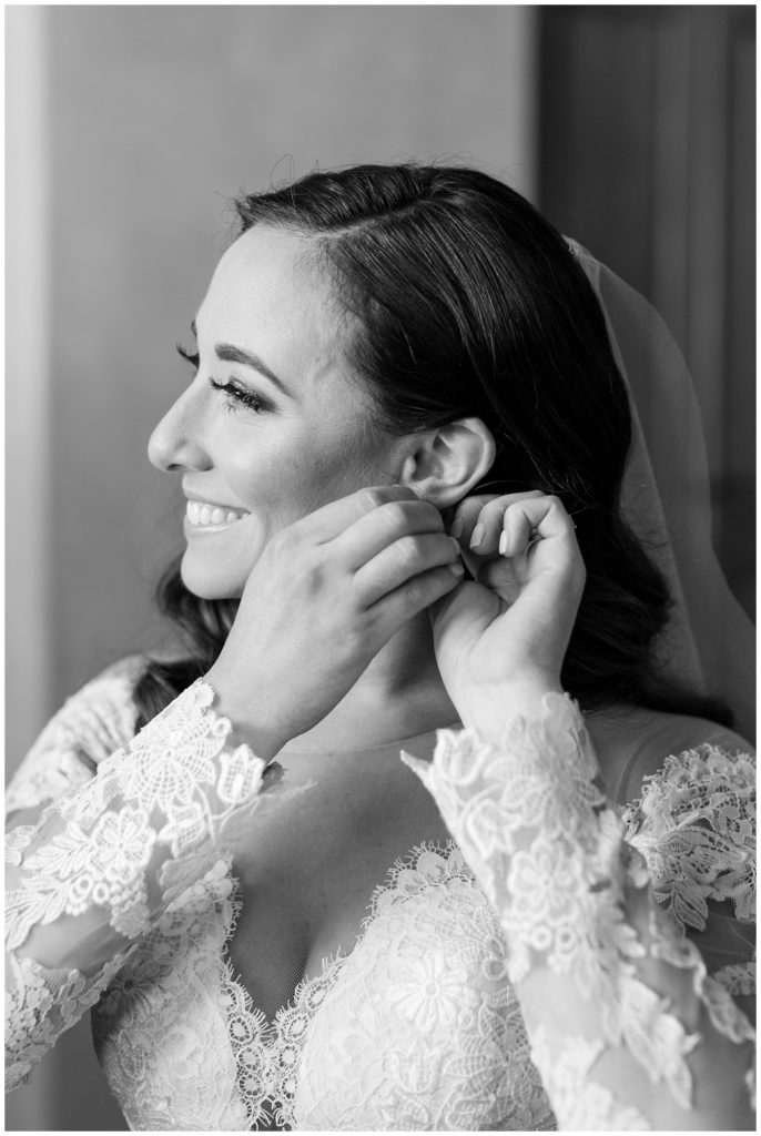 Bride putting earrings on at Bella Collina || The Ganeys