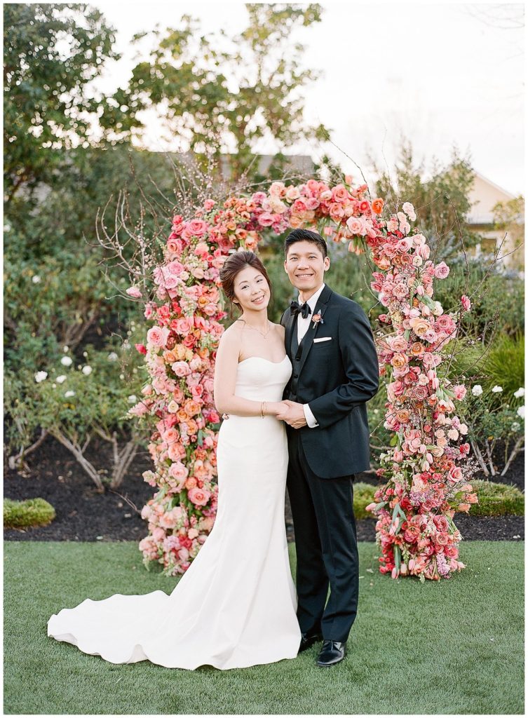 Couple portrait by floral ceremony arch by Gather Design Company
