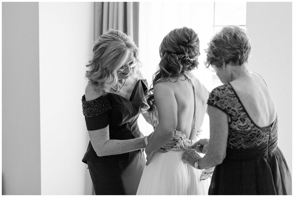 bride getting into Hayley Paige Teresa gown with help of mom and MIL