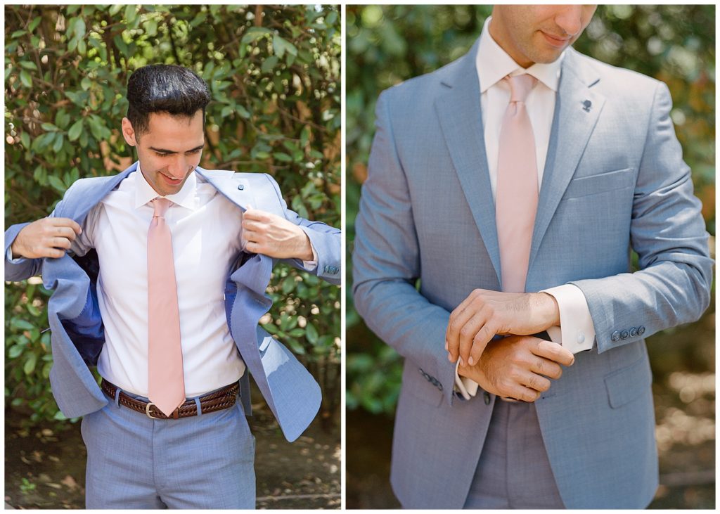 groom putting on light blue suit with silk pink tie