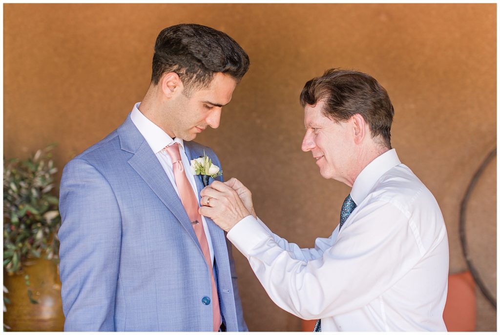 grooms father putting on boutonnière 