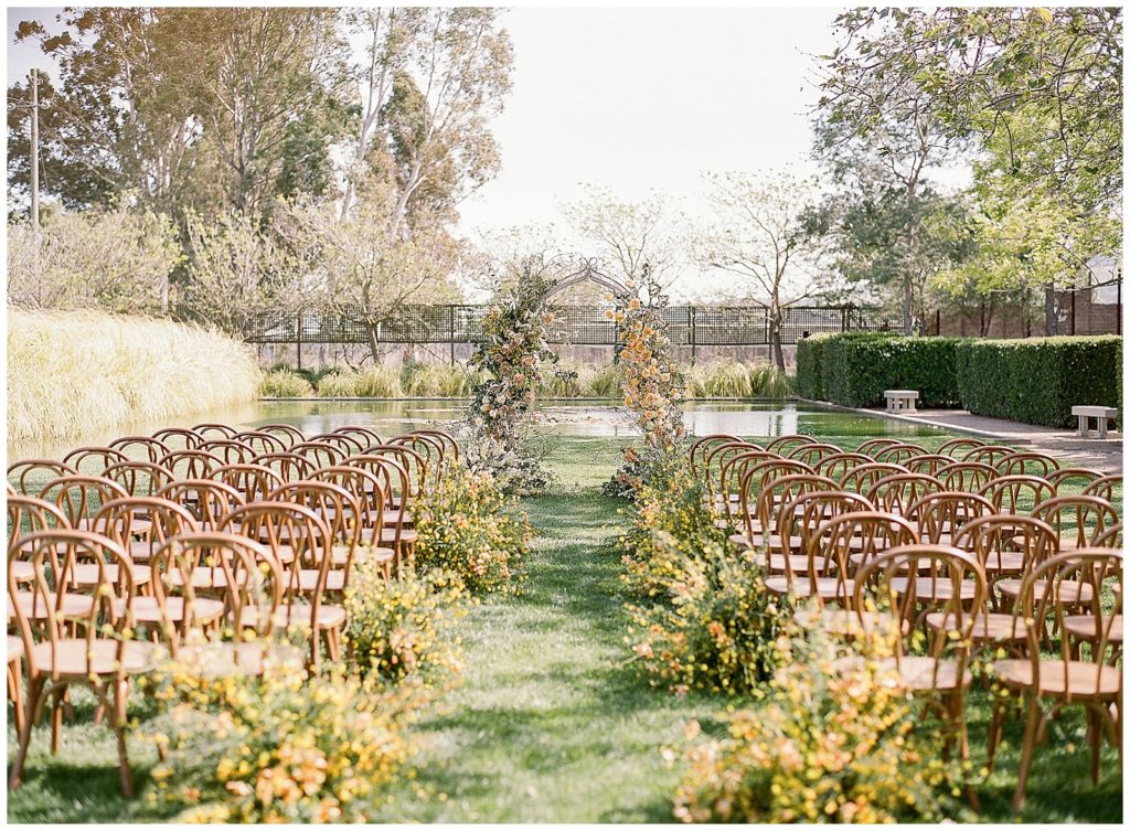 Spring wedding ceremony with arch and wooden bistro chairs natural aisle runner