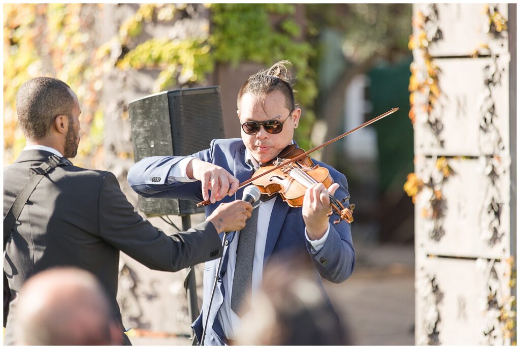 brides brother playing violin as she walks down the aisle